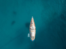 Aerial Bird's Eye View Drone Of Boat Docked In Mediterranean Tropical Beach With Turquoise - Sapphire Waters