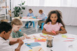 © LIGHTFIELD STUDIOS - multicultural preschoolers drawing pictures with pencils in classroom