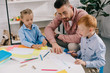© LIGHTFIELD STUDIOS - teacher in eyeglasses helping preschoolers with drawing at table in classroom
