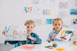 © LIGHTFIELD STUDIOS - portrait of cute kids showing drawings in hands at table in classroom