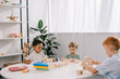 © LIGHTFIELD STUDIOS - multicultural little boys plying with wooden blocks at table in classroom