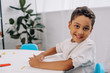 © LIGHTFIELD STUDIOS - smiling african american boy with plasticine looking at camera at table in classroom
