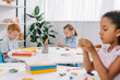 © LIGHTFIELD STUDIOS - selective focus of multiracial kids with plasticine at tables in classroom