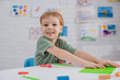 © LIGHTFIELD STUDIOS - portrait of smiling boy sitting at table with colorful plasticine for sculpturing in room