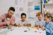 © LIGHTFIELD STUDIOS - multiracial preschoolers and teacher with plasticine sculpturing figures at table in classroom