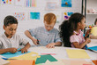 © LIGHTFIELD STUDIOS - portrait of focused multiethnic kids with scissors making paper applique in classroom