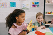 © LIGHTFIELD STUDIOS - portrait of multicultural classmates sitting at table with papers in classroom