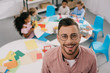 © LIGHTFIELD STUDIOS - selective focus of smiling teacher in eyeglasses and interracial kids at table in classroom