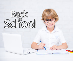 Sticker - back to school - happy little school boy in glasses doing homework with laptop