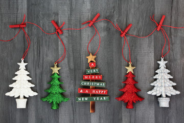 Wall Mural - Hanging Christmas tree bauble decorations on a string line with pegs on rustic wood background. Festive Christmas card for the holiday season.