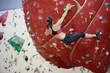 Photo from back of athlete woman on red climbing ball in sports hall