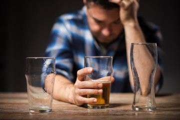 alcoholism, alcohol addiction and people concept - male alcoholic drinking beer from glass at night