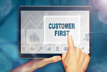 A hand selecting a customer first business concept on a computer tablet screen with a colorful background.