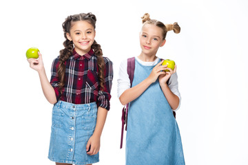 Wall Mural - smiling schoolchildren holding apples and looking at camera isolated on white