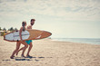 © luckybusiness - Happy couple surfers going together to surf at the beach .