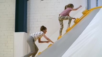Wall Mural - Follow shot of active children ascending stairs of inflatable mountain when spending time in indoor amusement park