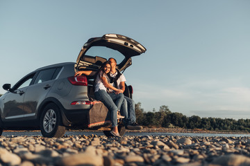 Wall Mural - Happy Couple on Roadtrip into the Sunset in SUV Car