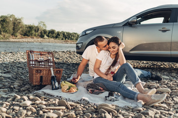 Wall Mural - Happy Traveler Couple on Picnic into the Sunset with SUV Car