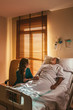 © MyMicrostock/Stocksy - Woman with patient in ward