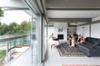 © Phillips Visuals/Stocksy - Family relaxing together in a contemporary house with a large area of glass.