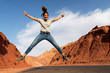 © Bisual Studio/Stocksy - A woman jumping in the air on a desert highway in Morocco