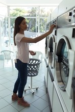 Woman Operating Washing Machine At Laundromat 