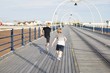© sally anscombe/Stocksy - Two children walking on the Pier together