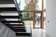 © Phillips Visuals/Stocksy - Couple arriving home viewed through glass entrance from modern staircase.