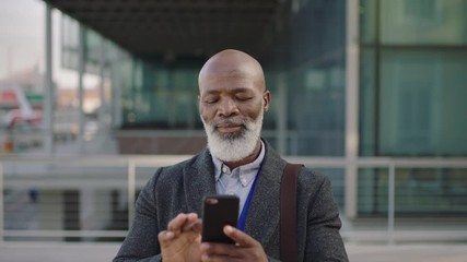 portrait of middle aged african american businessman texting browsing using smartphone mobile technology smiling enjoying reading messages
