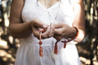© Lisa MacIntosh/Stocksy - woman wearing white dress holding prayer beads