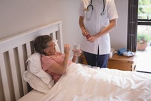 Physiotherapist Giving Medicine To Senior Woman