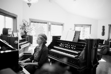 Happy Mature Woman Playing Piano And Organ In Home Studio