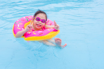 Little asian girl swimming with ring in the pool