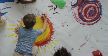 young diverse children paint colorful space pictures together on paper using paint brushes happy kid