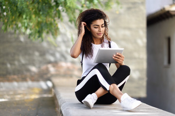 Poster - Young North African woman with looking at her digital tablet outdoors