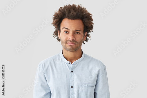 Puzzled Mixed Race Young Male With Afro Hairstyle Raises Eyebrow
