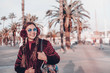© ClaudiK - Portrait of happy smiling woman standing on the square on sunny summer or spring day outside, cute smiling woman looking at you, attractive young girl enjoying travel, filtered image, flare sunshine.