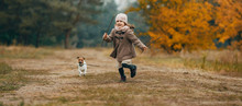 Child Girl Runs And Plays With His Dog During Walk.