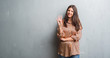 © Krakenimages.com - Young brunette woman over grunge grey wall showing and pointing up with fingers number four while smiling confident and happy.