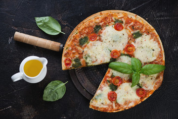 Poster - Traditional italian pizza with different types of cheese and tomatoes, above view on a dark brown stone background, horizontal shot