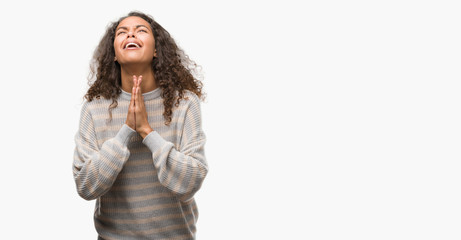 Canvas Print - Beautiful young hispanic woman wearing stripes sweater begging and praying with hands together with hope expression on face very emotional and worried. Asking for forgiveness. Religion concept.