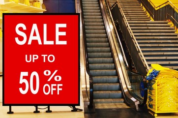 big sale 50% mock up advertise billboard or advertising light box in front of escalator in modern department store shopping mall, special offer, commercial, marketing and advertisement concept