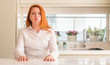 © Krakenimages.com - Redhead woman at kitchen puffing cheeks with funny face. Mouth inflated with air, crazy expression.