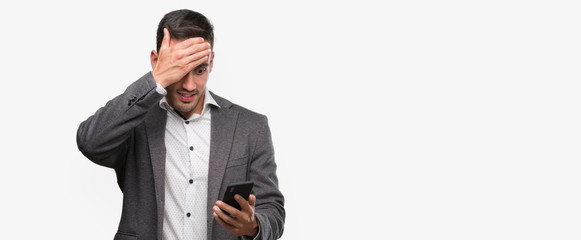 Wall Mural - Handsome young man using smartphone stressed with hand on head, shocked with shame and surprise face, angry and frustrated. Fear and upset for mistake.