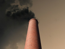 Billowing Brick Smokestack Pouring Pollution Into A Dark Stormy Sky.