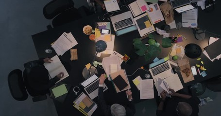 Wall Mural - multi ethnic business people working late planning strategy for corporate project developing creative ideas in messy boardroom above view