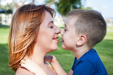 young and beautiful caucasian woman looking at her son, face to face close up portrait, mother child