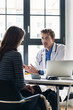 © Kzenon - Young devoted doctor holding an X-ray while listening with attention to his female patient during a private consultation in the office