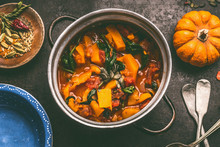 Close Up Of Tasty Pumpkin Dish In Cooking Pot On Dark Rustic Kitchen Table Background, Top View. Pumpkin Stew.   Autumn Seasonal Rustic Country Food