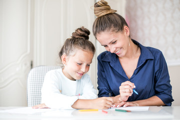 Wall Mural - Happy family. Mother and daughter together paint and draw. Adult woman helps the child girl